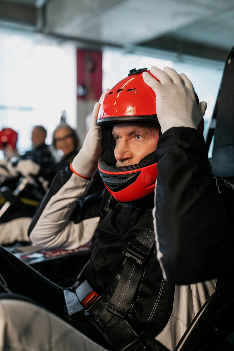 Un homme âgé portant un casque se prépare pour une course de karting en salle.